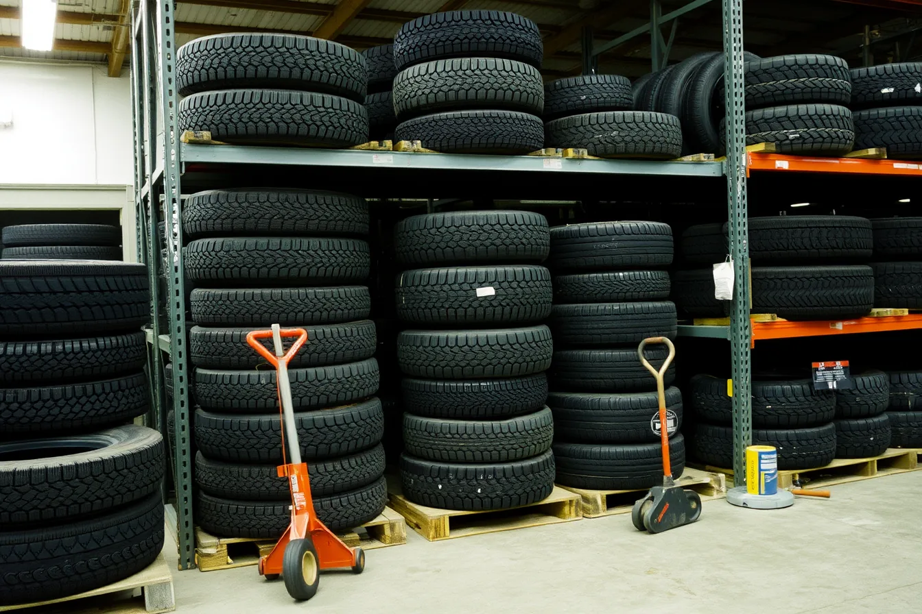 Stacked tire tread stock on warehouse rack shelving in a shop. Sourcing tires in Canada compared with buying from US distributors